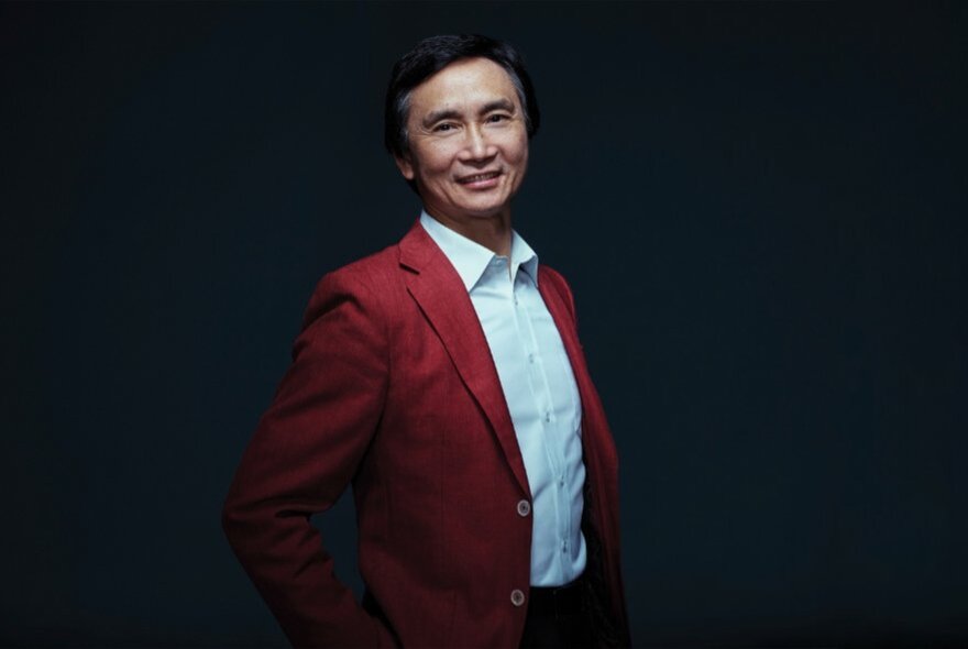 Li Cunxin, wearing a red jacket and white shirt.