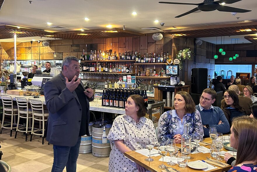 Patrons at a special wine night at a bar listening to a wine expert speak.
