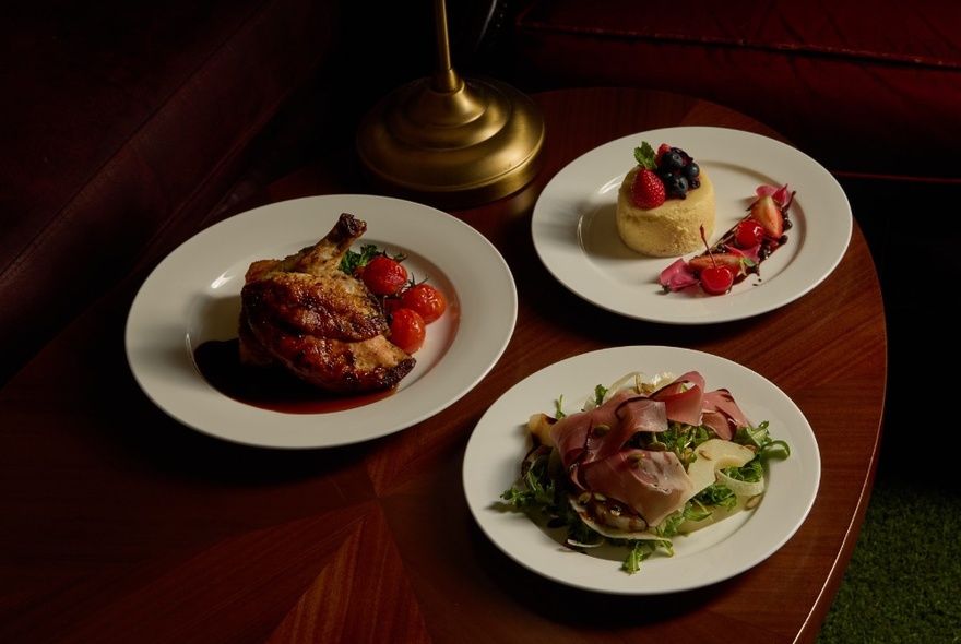 Three plates of food on a wooden table in a restaurant.