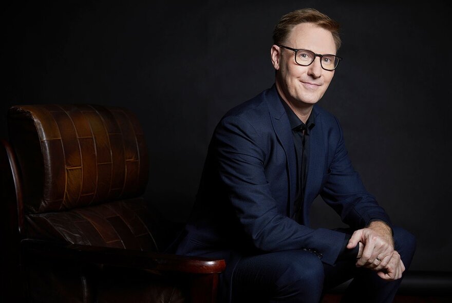 MSO Principal Guest Conductor Benjamin Northey sitting on an armchair with hands together.