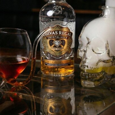 A bottle of whisky next uniquely shaped glass with a curved stem from the bottom that functions as a straw.