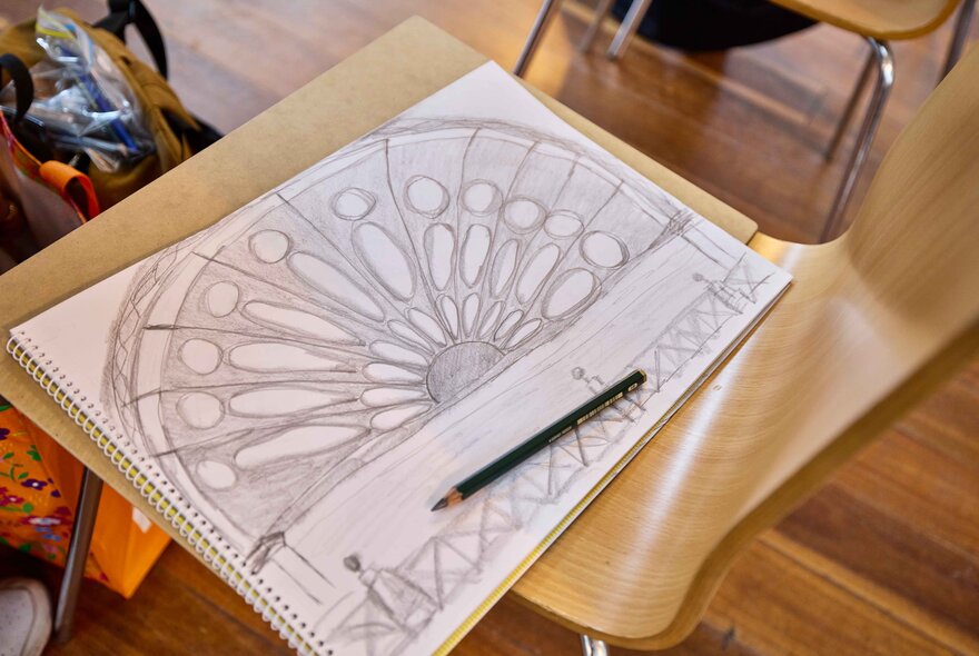 A drawing class sketch on paper with a pencil resting on the drawing, focused on classical architecture, and a gothic rose window design. 
