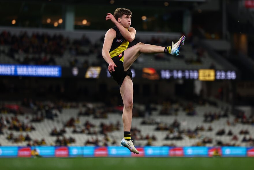  AFL football player kicking a ball on the field during a match.