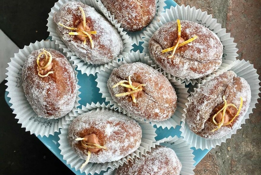 Several Italian-style bombolini doughnut, dusted with sugar and viewed from above.