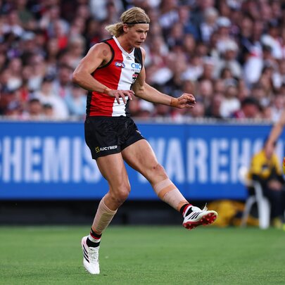 St Kilda AFL football player kicking a yellow ball during a match.