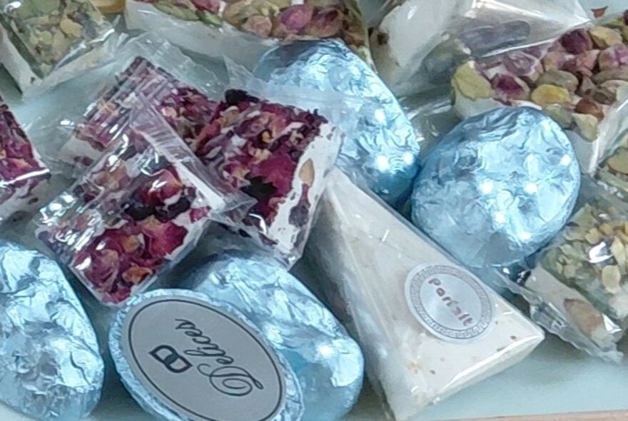 A selevetion of wrapped sweets and pistachio nuts in small bags. 