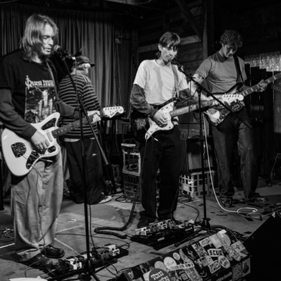 A black and white photograph of a three-guitarist band on stage.