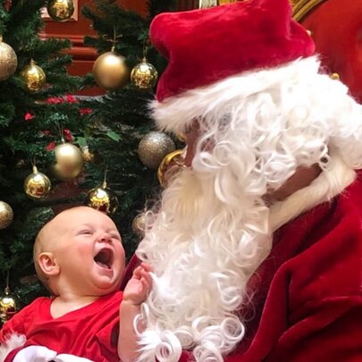 A smiling baby sitting on Santa's lap. 