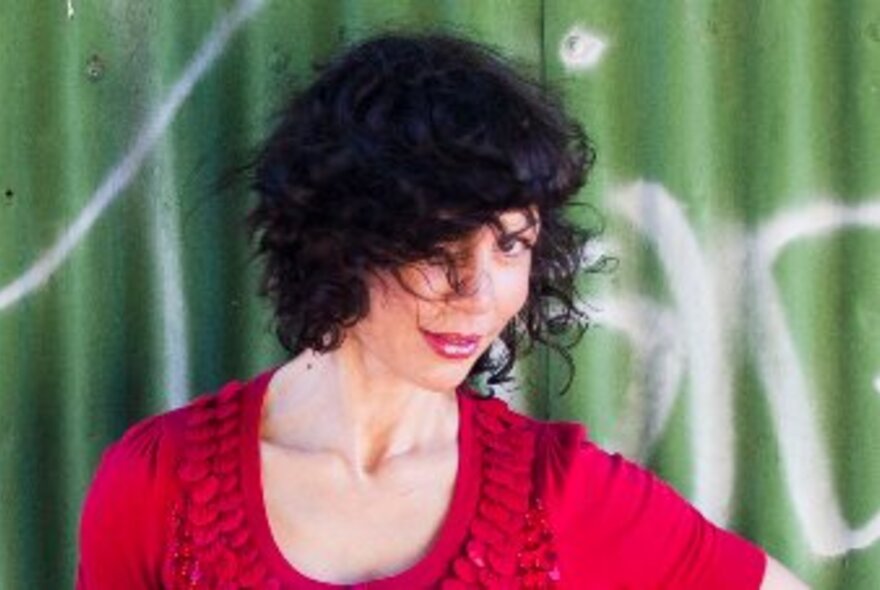 Sultry singer Jackie Bornstein dressed in red with her dark hair covering one eye.