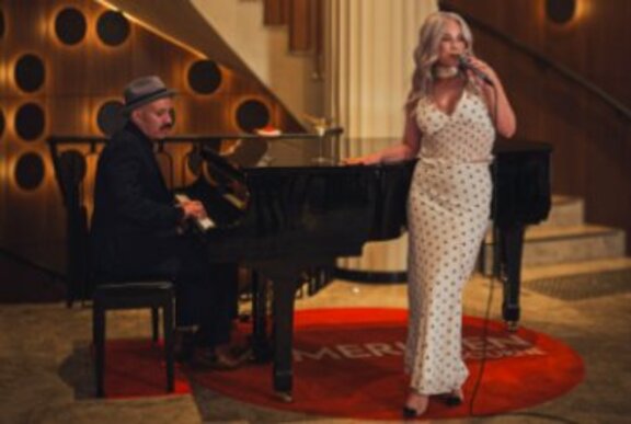A singer performing next to a piano.