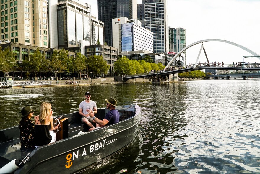 A group of friends driving a small boat on the Yarra River in Southbank, Melbourne.