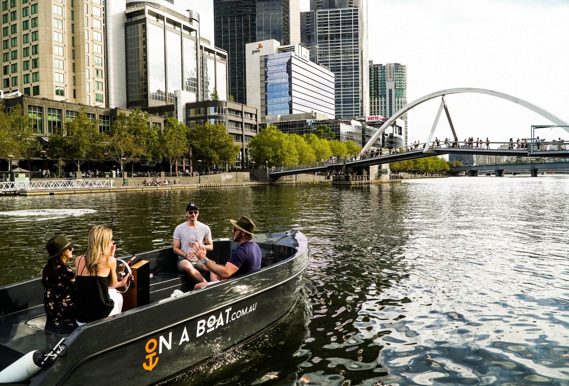A group of friends driving a small boat on the Yarra River in Southbank, Melbourne.