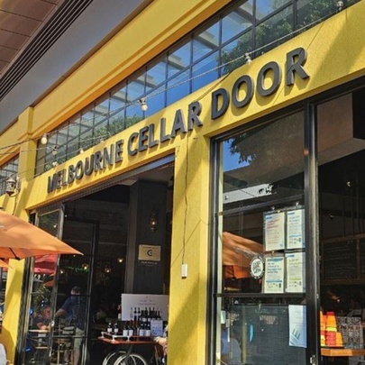 The yellow-painted entrance to Melbourne Cellar Door, with orange umbrellas and patio heaters out the front.