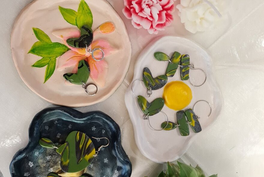 Several trays of green clay earrings, including a tray designed like a fried egg.