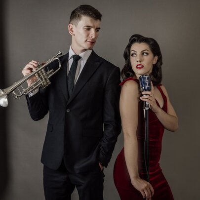 Jazz musicians, Lumen Duo, posing with a trumpet and a microphone.