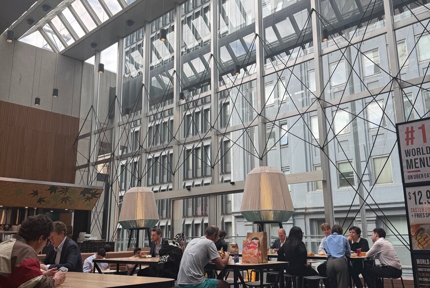 The interior of a foodcourt with large steel-framed windows.