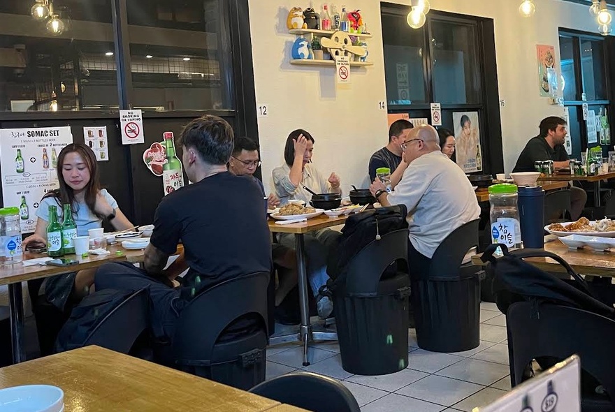 People seated at tables inside a casual restaurant eating and drinking.