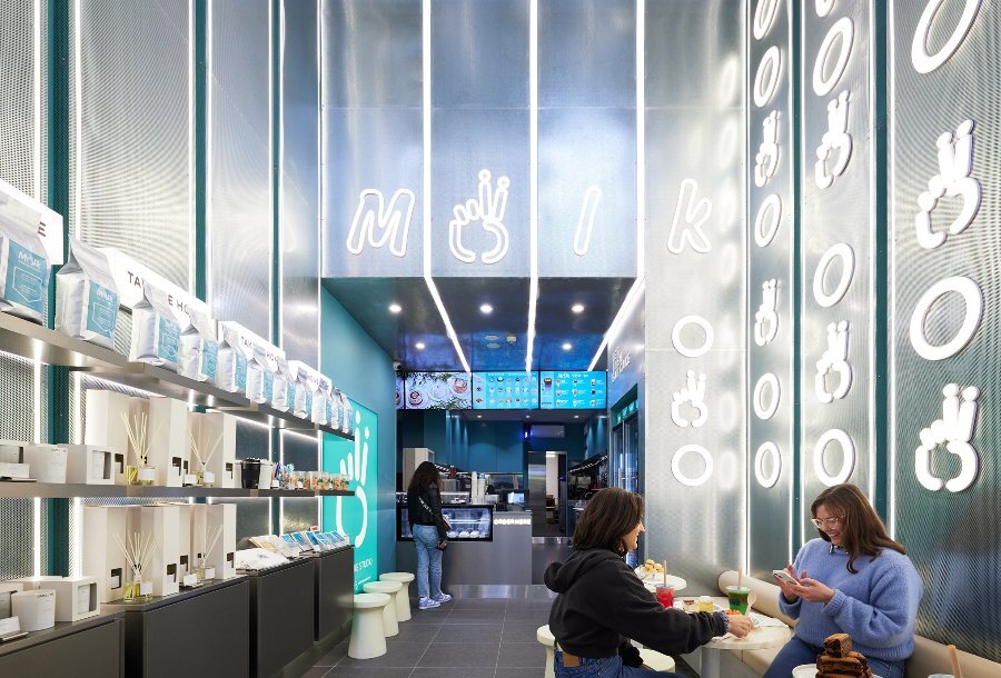 Two friends are sitting in a neon-lit cake shop.