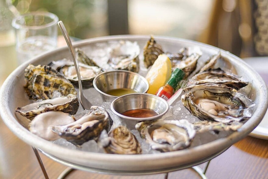 Plate of raw oysters with slice of lemon.