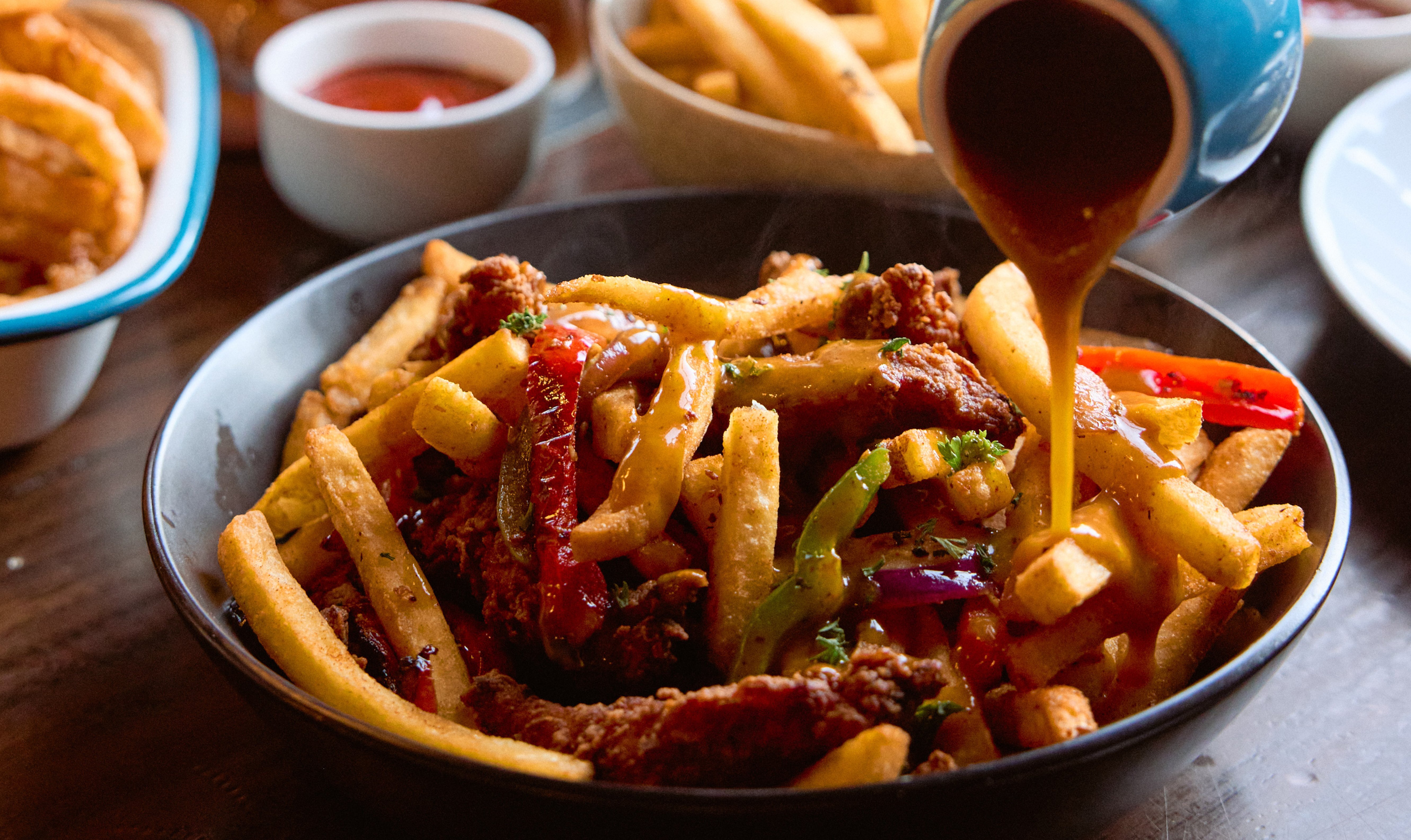 An Irish spice bag with chips, chicken fingers, vegetables and gravy. 