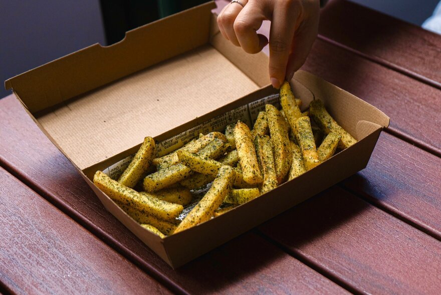 A cardboard box filled with chips, resting on a timber table.