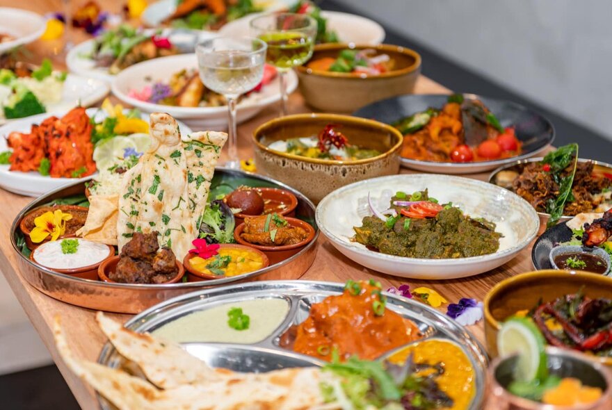 A table in a restaurant covered in plates of South Indian food.