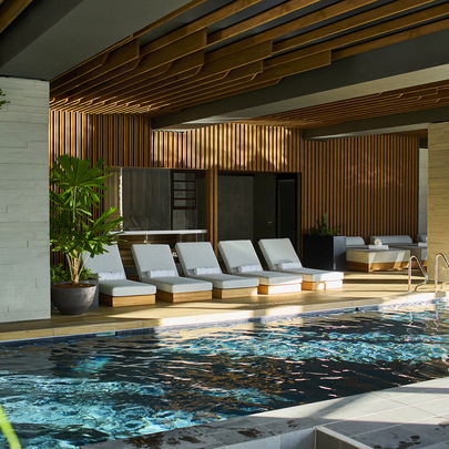 A hotel pool with a row of sun lounges.