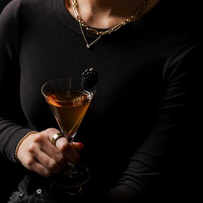 A woman wearing black holding a cocktail.