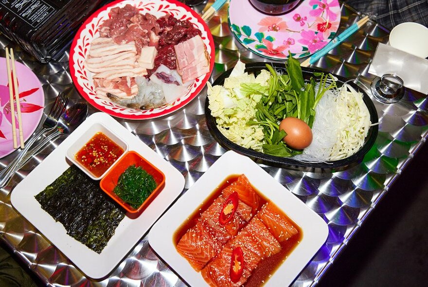 A silver table filled with Thai hotpot ingredients.