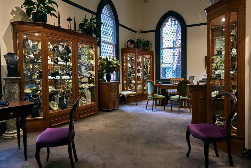 An old-fashioned jewellery store with arched windows, timber display cabinets and purple velvet chairs.