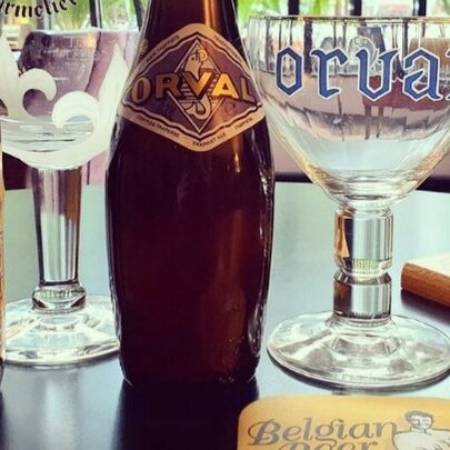 A selection of Belgian beers in small bottles, and glasses lined up on a bar.