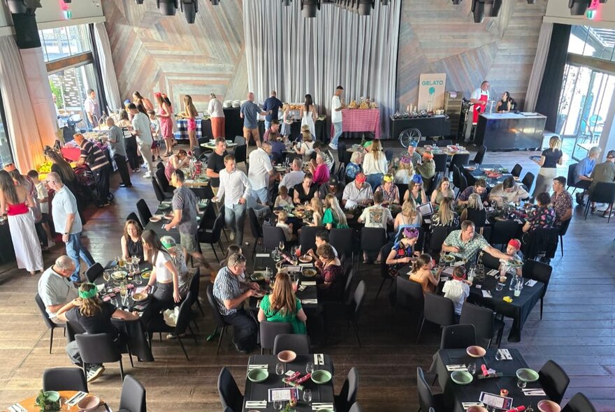 Looking down from high up at an event space with people a tables and a buffet.