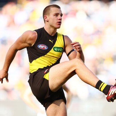 Richmond AFL football player kicking a ball during a match.