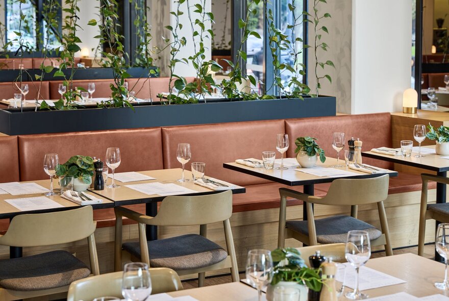 Hotel restaurant with bench seating and tables set for dinner.