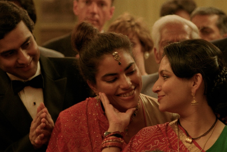 An Indian family at an event, wearing formal dress and saris.