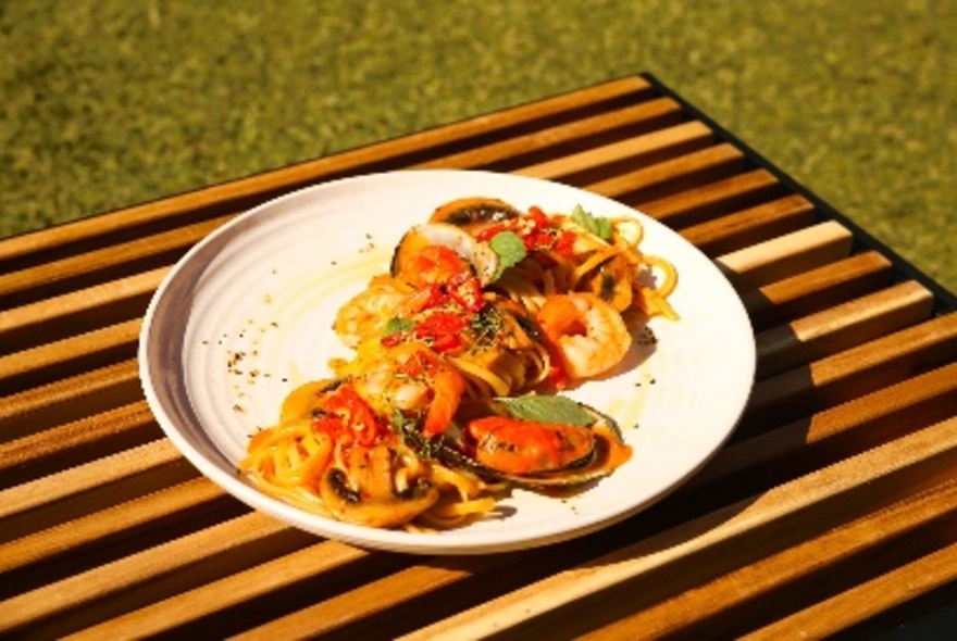 A breakfast dish with mushrooms in bright sunlight on a wooden striped board on fake grass. 