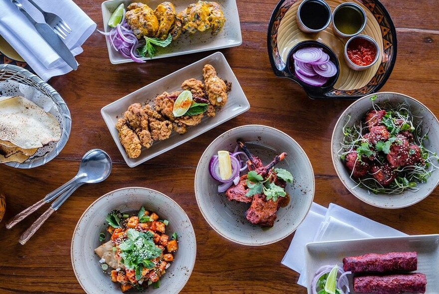 An array of Indian dishes including tandoori chicken and condiments.