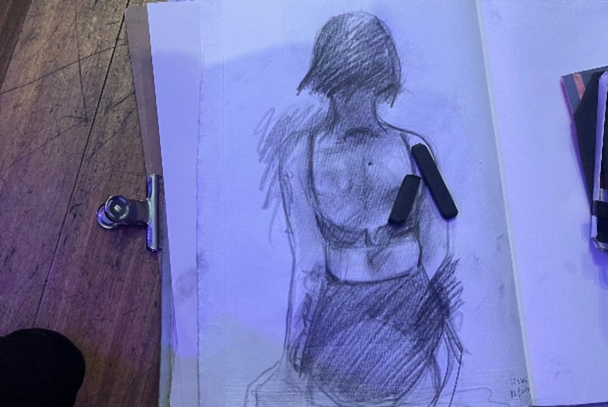 A life drawing sketch showing the back of woman in charcoal. 