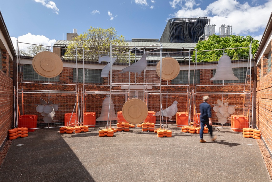 Exterior open-air courtyard filled with a large man-made percussive instrument and a person.