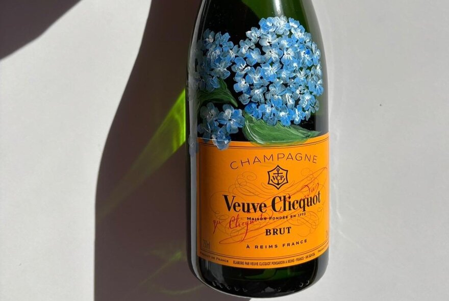 Bottle of champagne with hand-painted blue flower.