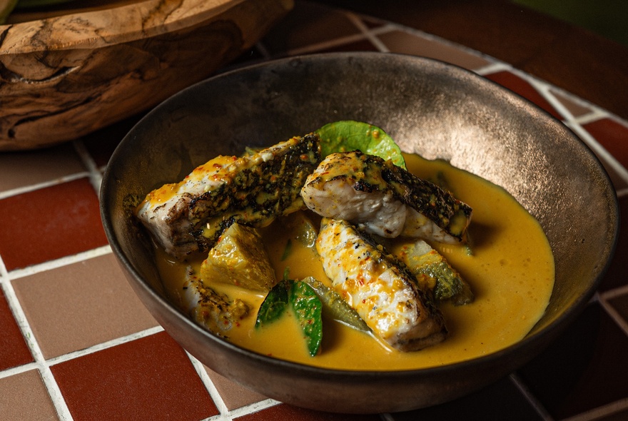 A Thai fish curry in a bronze bowl.