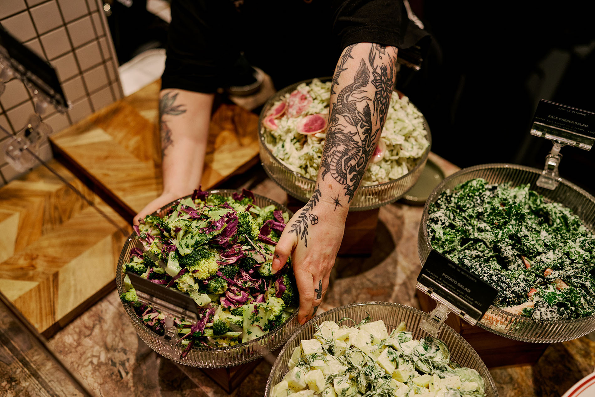 Someone putting a salad down in a display.