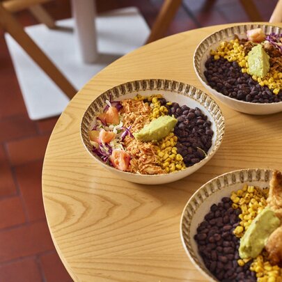 Bowls of Mexican rice dishes on a round wooden table.