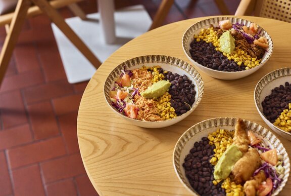 Bowls of Mexican rice dishes on a round wooden table.