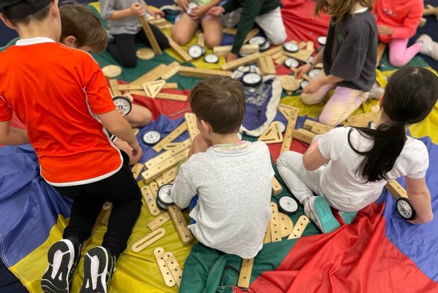 Kids sitting on the floor building with wooden blocks.
