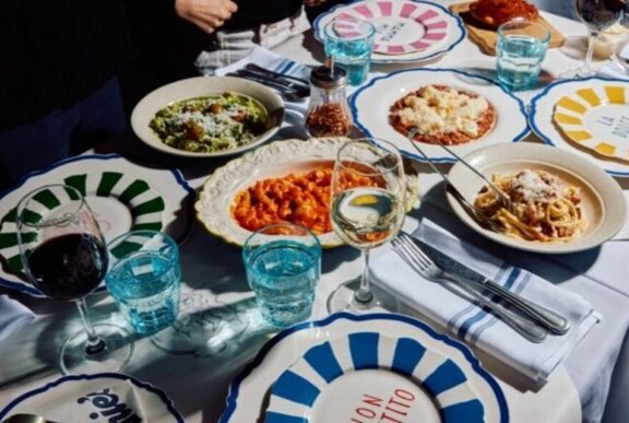 Dishes of pasta on a table with brightly decorated plates and tableware