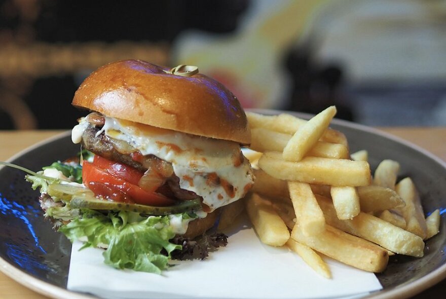 A beef and egg burger on a plate with chips 