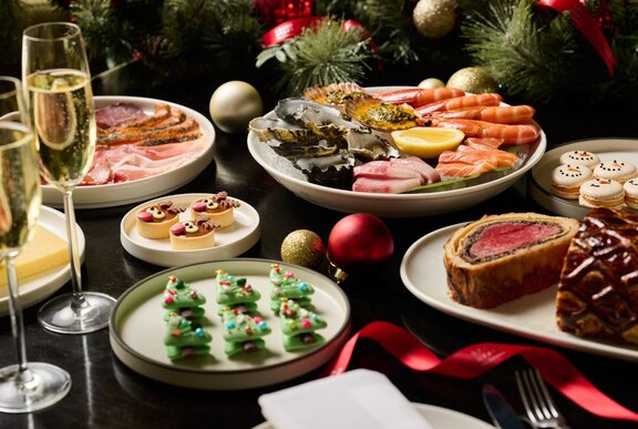 A colourful display of festive fare including Christmas tree cookies, Beef Wellington and champagne glasses.