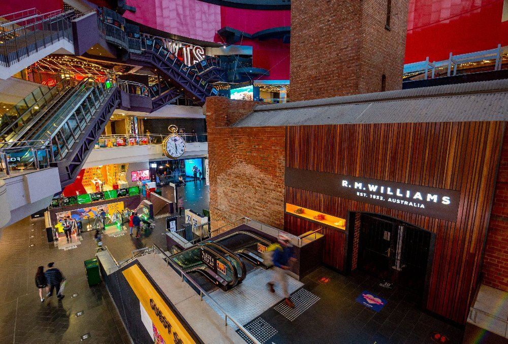 A large brick building surrounded by escalators inside a shopping centre.