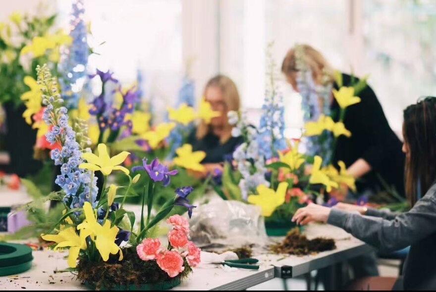 A traditional Chinese flower arrangement celebrating the Lunar New Year, alongside others that have been produced all together in a workshop.